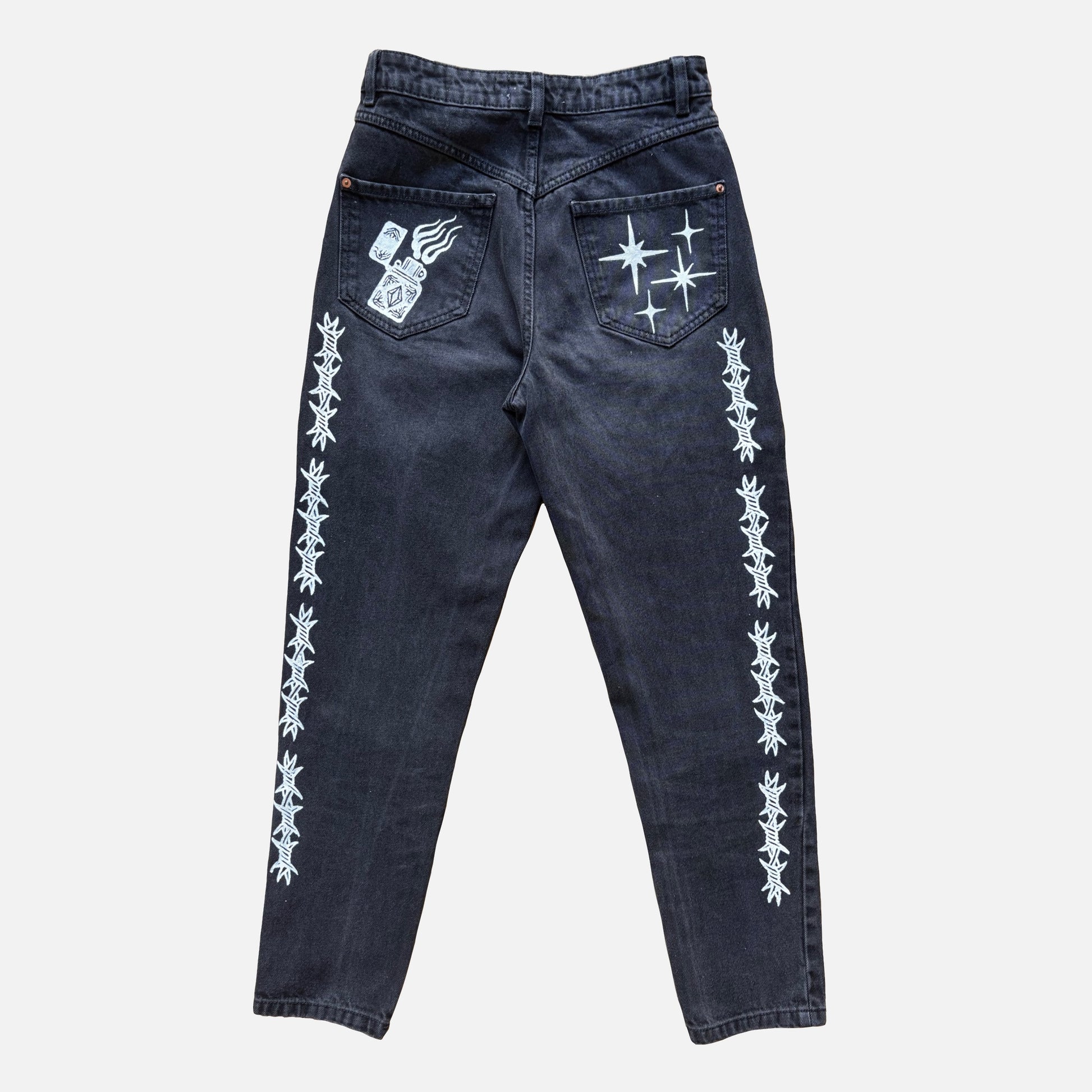 Dark washed denim jeans shown from the back, featuring white printed barbed wire patterns down both legs and white graphic designs on the back pockets.