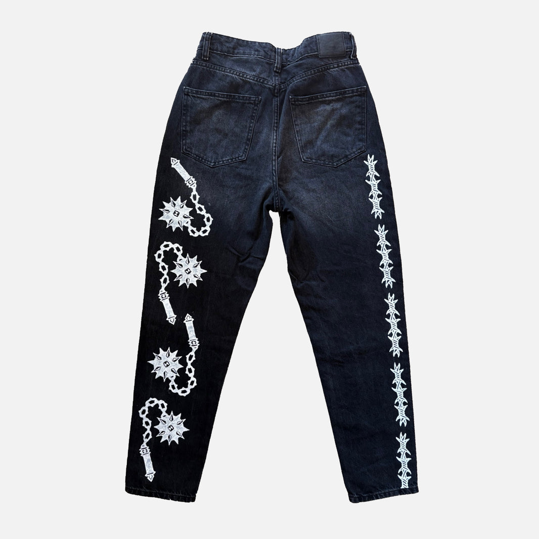 Dark washed denim jeans shown from the back, featuring white printed barbed wire and flail motifs running down both legs.