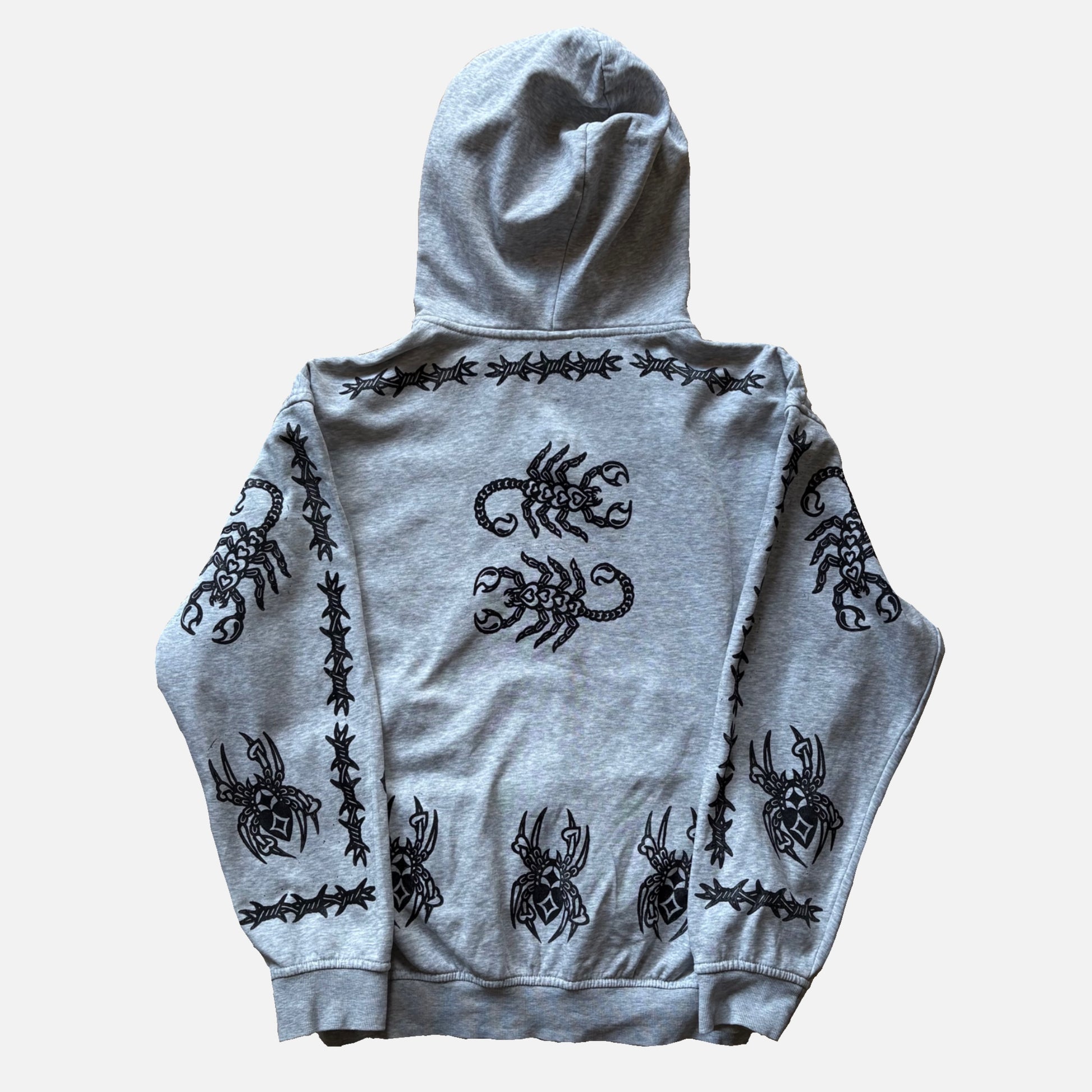 A light gray heather hoodie shown from the back, featuring black graphic prints of scorpions and barbed wire along the shoulders, sleeves, and lower back, laid flat against a light gray background.